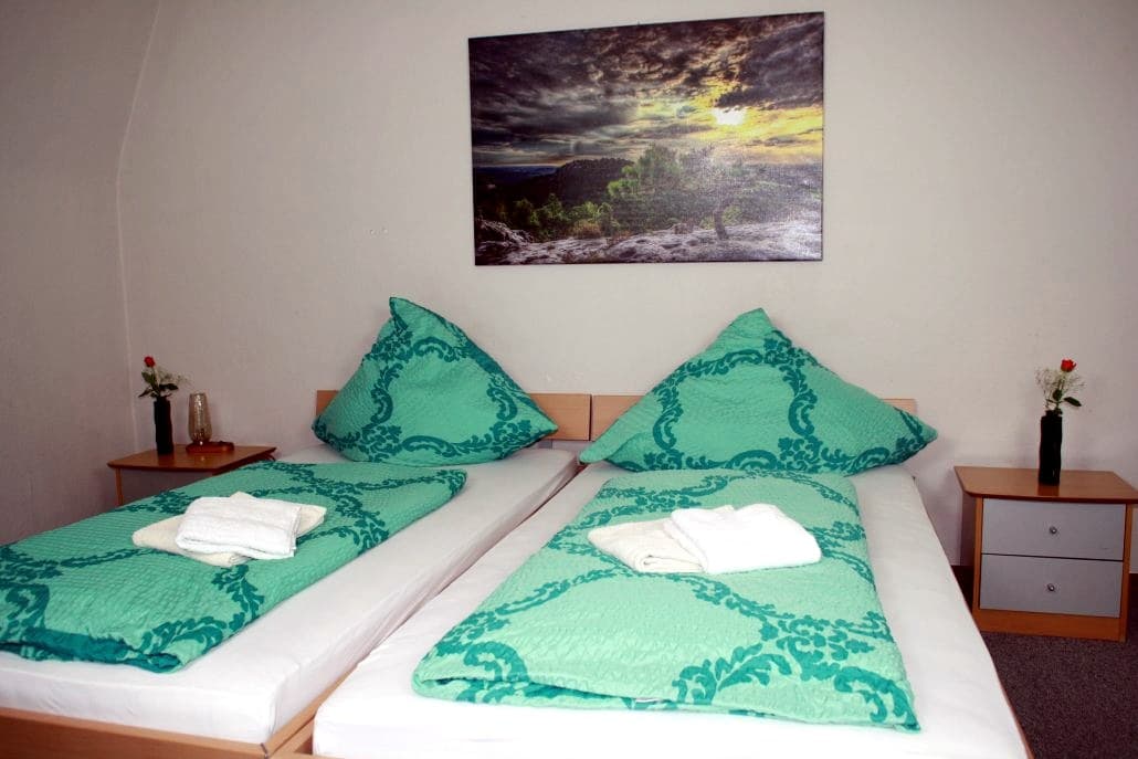 Helles Zimmer mit zwei Betten in Grün und einem Landschaftsbild
